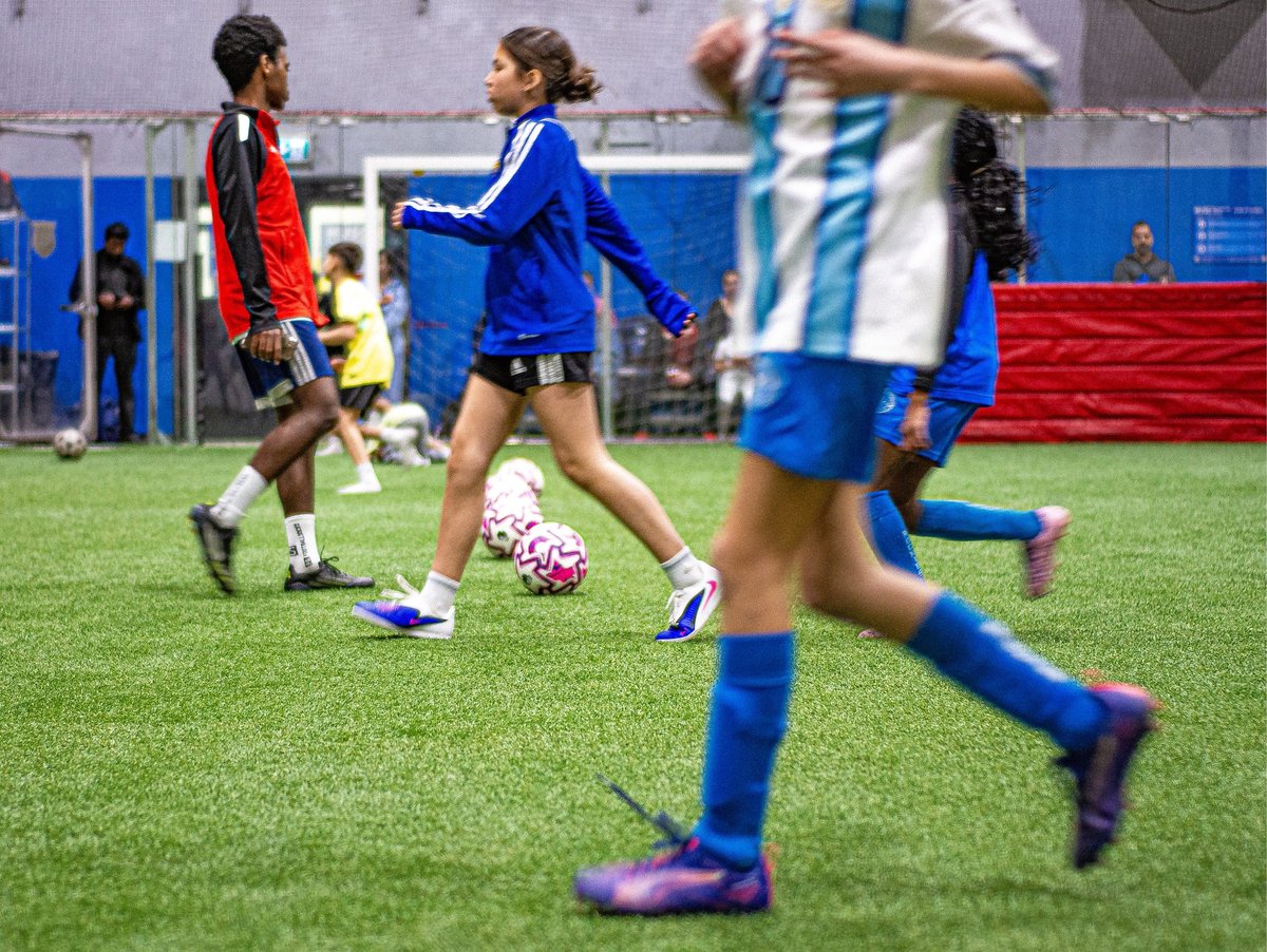 Young soccer players in blue and red jerseys competing for the ball during a youth football match on artificial turf